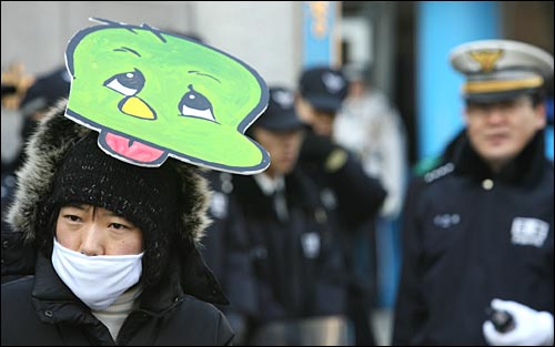 마스크를 착용한 인권활동가가 '아기공룡 둘리' 가면을 쓰고 있다. 